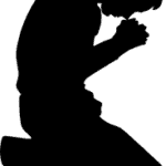A silhouette of a person kneeling and praying, symbolizing hope and resilience in the fight against human trafficking.